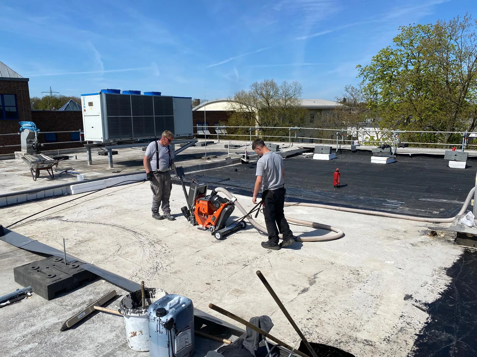 Kugelstrahlmaschine mit direkter Absaugung bei der Untergrundvorbereitung eines Flachdachs aus Beton Kugelstrahlmaschine mit direkter Absaugung bei der Untergrundvorbereitung eines Flachdachs aus Beton